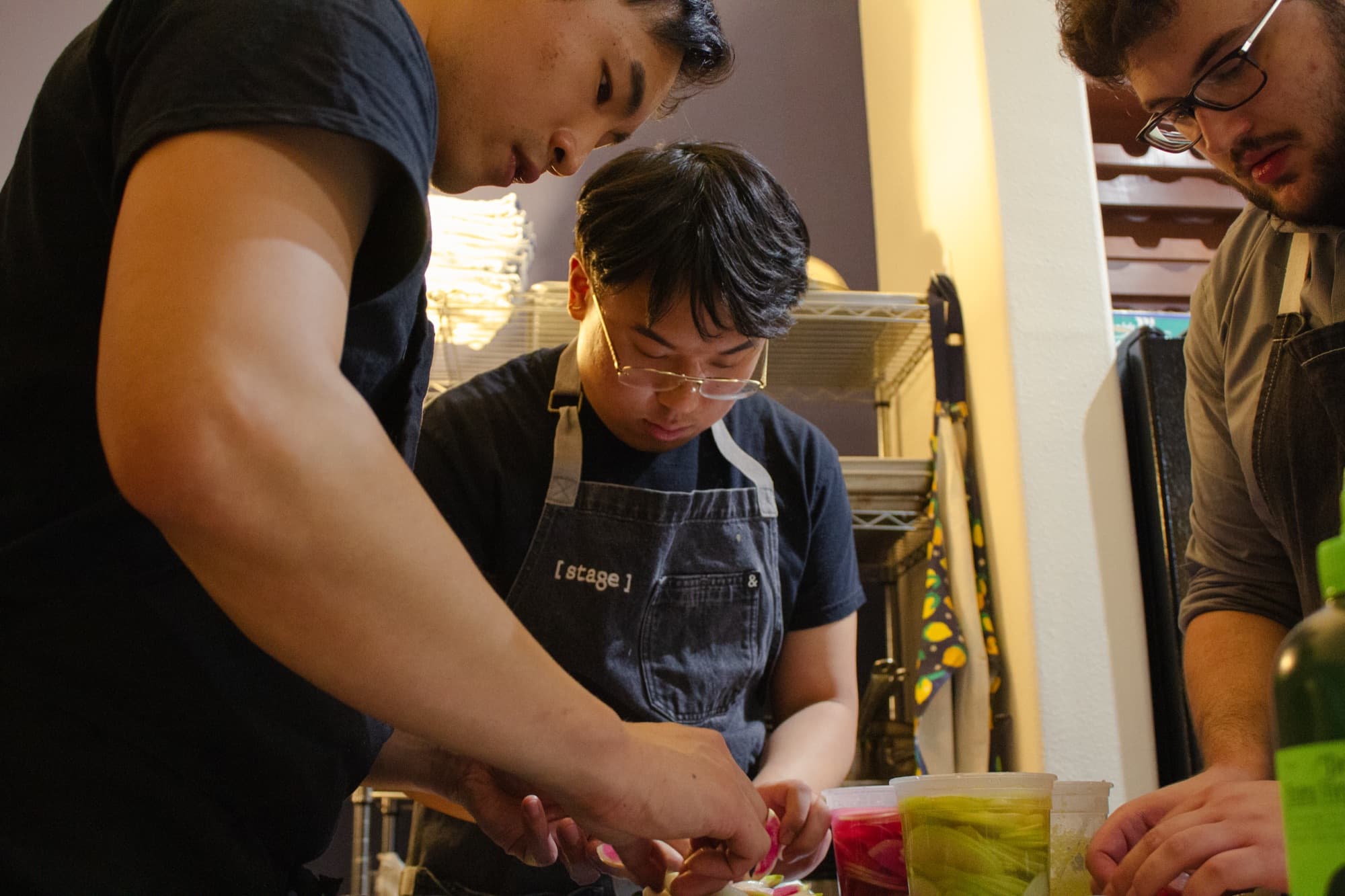 Chefs in [ stage ] aprons plating together